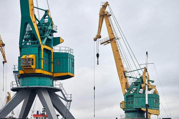 Massive harbor cranes in seaport. Heavy load dockside cranes in port, cargo container yard, container ship terminal. Business and commerce, logistics