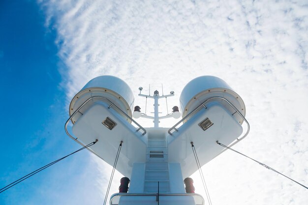 Mast of a large motor yacht with navigational signal lights radars satellite dishes and equipment