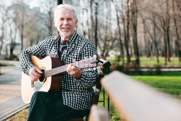 Master akkoord. Aardige volwassen man camera kijken en gitaar spelen