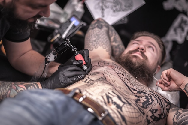 Master of the art of tattooing demonstrates the process of getting tattoo in tattoo studio.