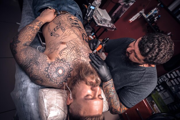 Master of the art of tattooing does tattoo on the skin of his client in studio.