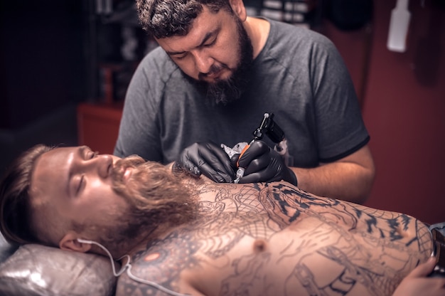 Maestro dell'arte del tatuaggio durante una sessione di tattoo artist tattoo studio