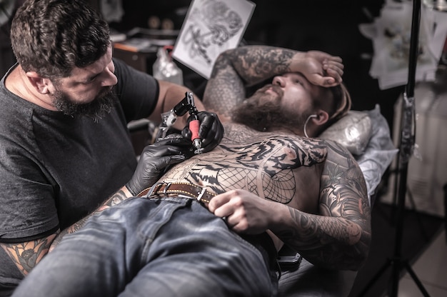 Maestro dell'arte del tatuaggio in posa nel salone di tatuaggi