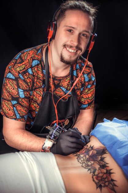 Foto maestro dell'arte del tatuaggio lavorando su una mitragliatrice professionale nel salone