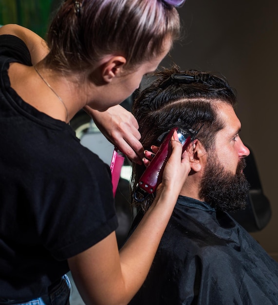 Master Barber doet het kapsel en de styling met elektrisch scheerapparaat aan Guy Concept Barbershop