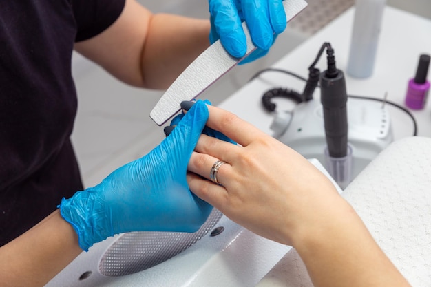 The master in the beauty salon makes the girl a manicure.