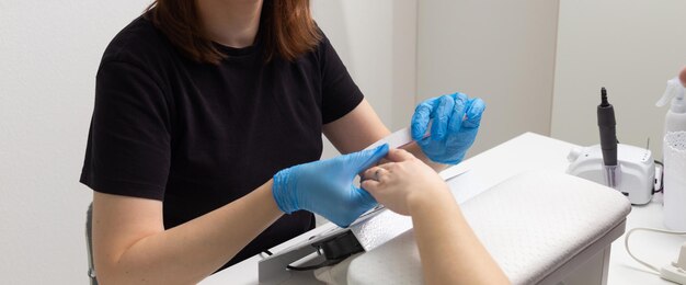 Il maestro nel salone di bellezza fa una manicure alla ragazza.