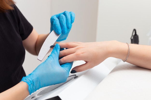 Il maestro nel salone di bellezza fa una manicure alla ragazza.