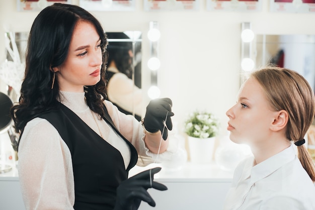 Master brow artist corrects eyebrows using a thread in the salon effectively