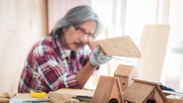 Un maestro falegname sta ispezionando il legno nel suo laboratorio di falegnameria.