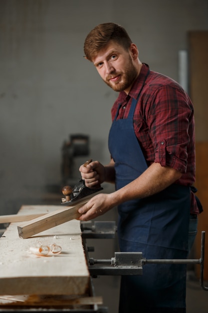 Master carpenter in shirt and apron in the workshop