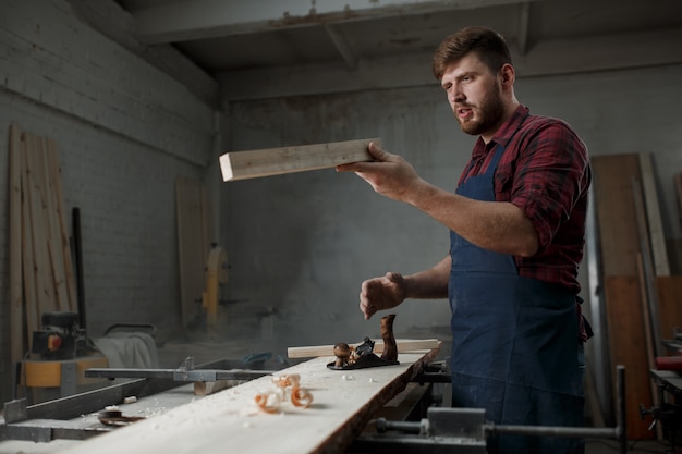Master carpenter in shirt and apron in the workshop