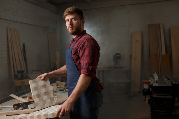 Master carpenter in shirt and apron in the workshop