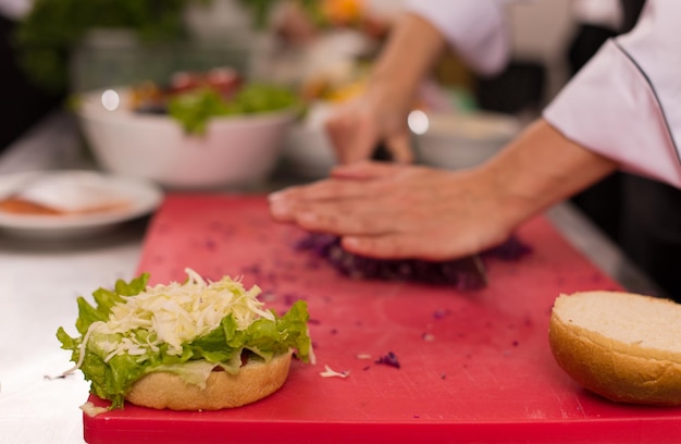 rastaurant 부엌에서 버거를 위한 샐러드를 자르는 마스터 셰프