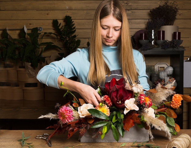 花束と仕事で女性の花屋のマスタークラス。な秋の花の花束を作る若い女性。フラワーショップでのビジネスの女性花屋の肖像画