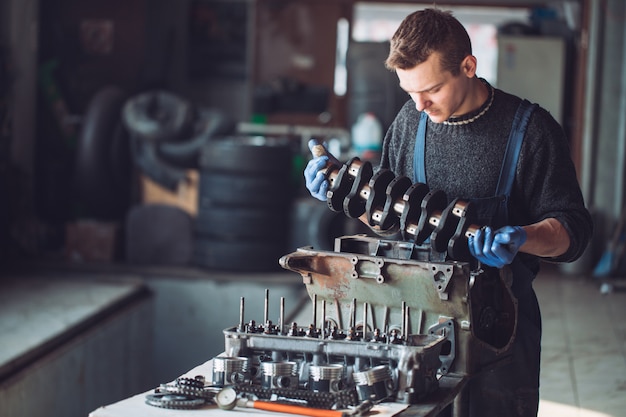 Il maestro raccoglie un motore ricostruito per l'auto.