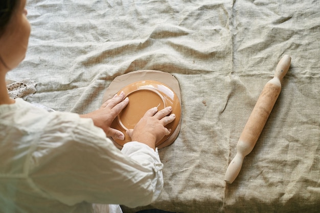 Master craftsman rolls the clay on the table, transfers the napkin pattern to the clay mass