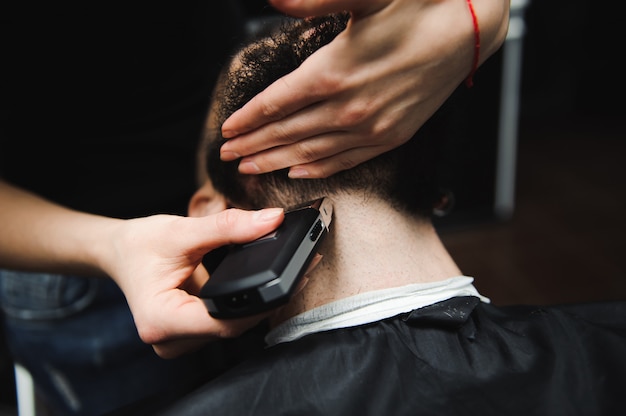 Master cuts hair and beard of men in the barbershop, hairdresser