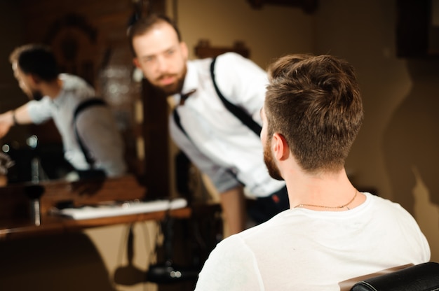 Il maestro taglia i capelli e la barba degli uomini nel barbiere