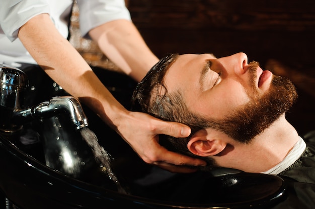 Master cuts hair and beard of men in the barbershop