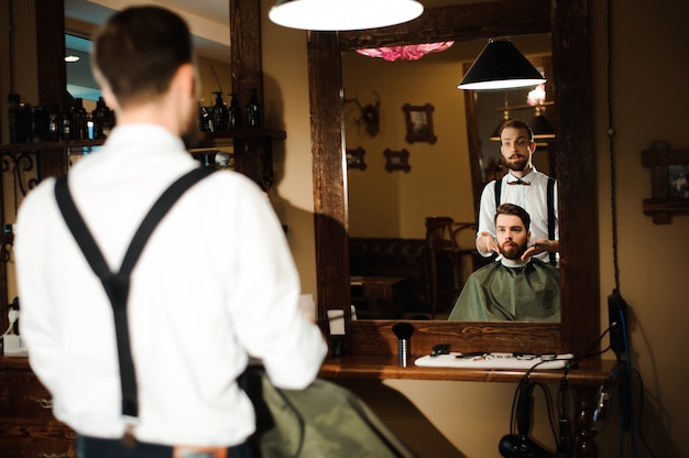 Foto il maestro taglia i capelli e la barba degli uomini nel barbiere