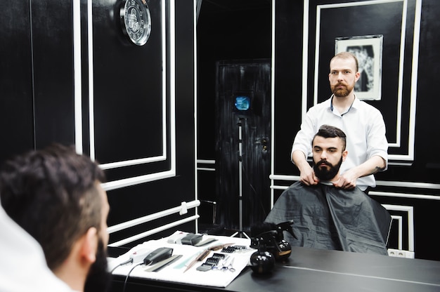 Master cuts hair and beard of men in the barbershop