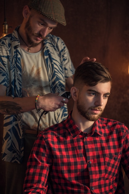 Foto il maestro taglia i capelli e la barba degli uomini