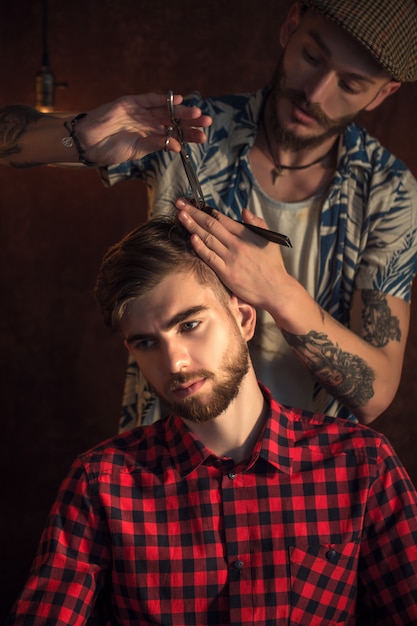 Foto il maestro taglia i capelli e la barba degli uomini