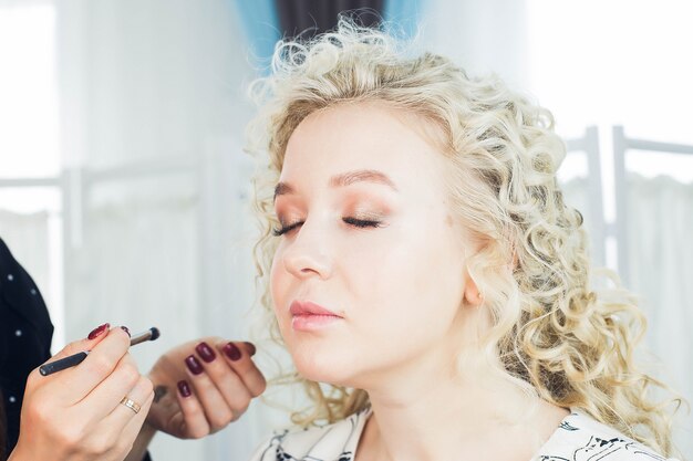 Photo the master does a beautiful blonde makeup in a beauty salon