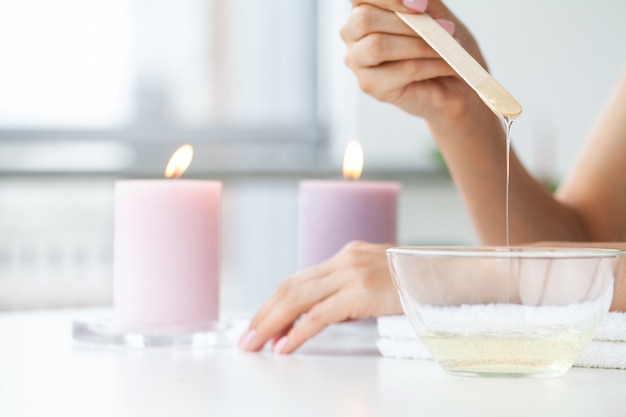 Il maestro esegue l'epilazione delle mani con l'aiuto della cera calda in pasta di zucchero nel salone di bellezza.