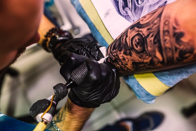 Фото Мастер рисования татуировки на руке
