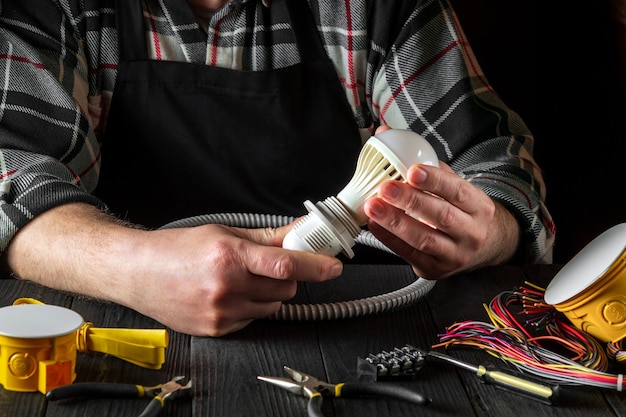 master electrician turns on light bulb close up of worker hands on desktop in workshop