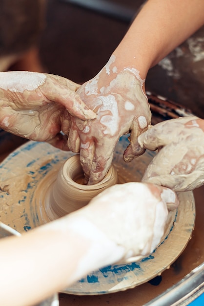 The master helps the student to create a figure in pottery.