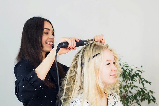 The master makes a hairstyle for a girl, beautiful curls