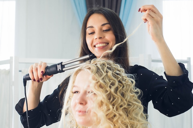 The master makes a hairstyle for a girl, beautiful curls