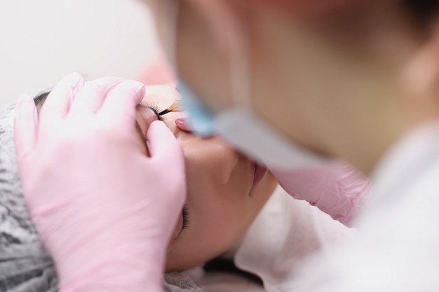 Il maestro realizza il trucco permanente per le palpebre del cliente nella scelta del trucco permanente del salone