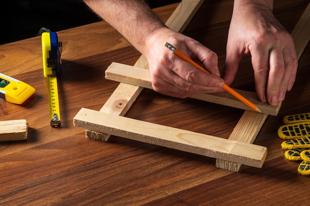 The master marks the distance on the wooden plank with a pencil.
