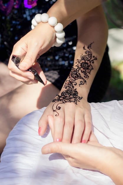 Master mehndi draws henna on a female hand