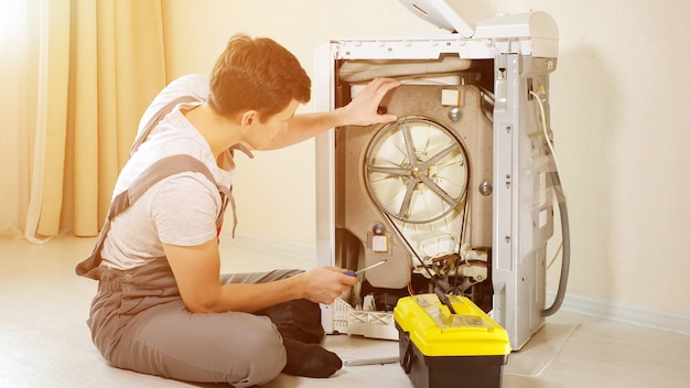 Master opens back panel of broken washing machine