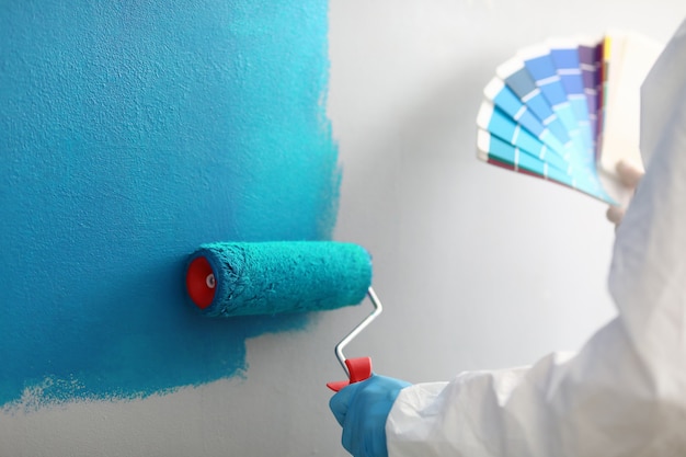 Master painter holds in his hands color palette with shades of blue