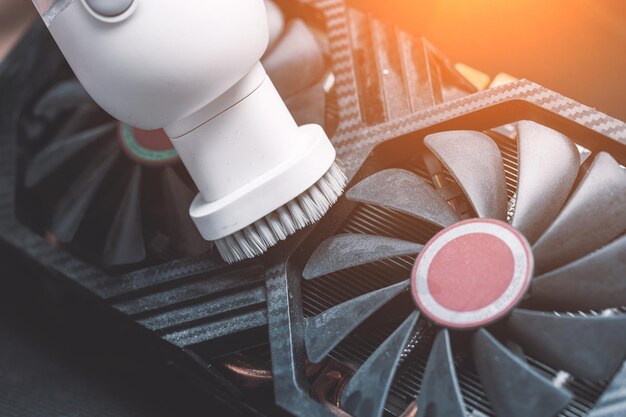 The master performs maintenance of a modern video card cleaning the video card with a vacuum cleaner