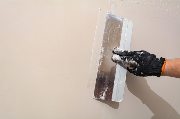 マスターは壁を漆喰で塗りますアパートの修理用の道具
