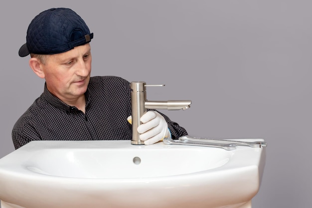 The master plumber screws the faucet to the sink in the bathroom