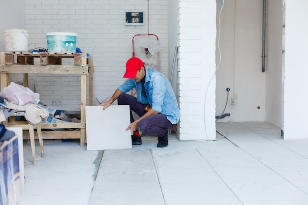 Il maestro mette le piastrelle di ceramica sul pavimento