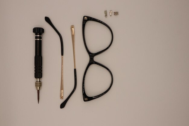 Photo a master repairs eyeglasses disassembled glasses and a screwdriver nearby