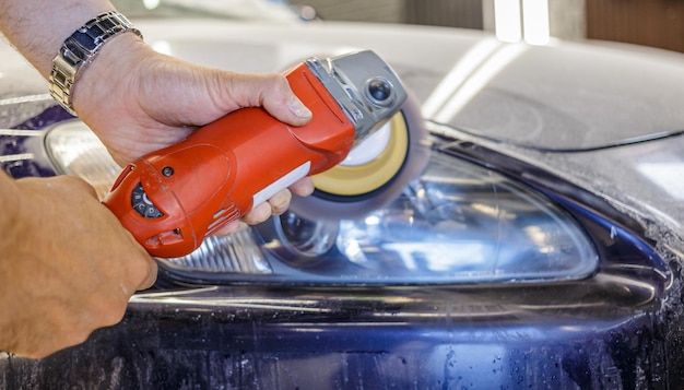 Master reparateur polijsten koplampen van auto in werkplaats met behulp van machine close-up