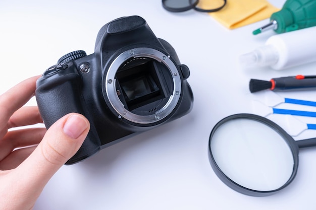 Master's hand houdt dslr-camera, camera-reinigingsaccessoires op witte achtergrond