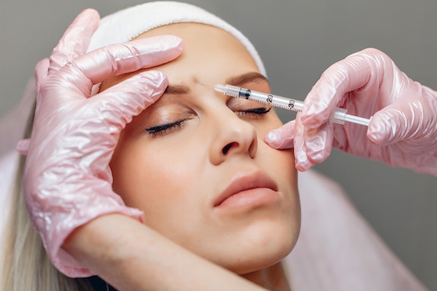 Master schoonheidsspecialist anti-aging botox injecties te geven aan alovely jonge vrouw met gladde huid.