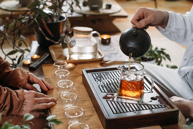 Master serving traditional chinese tea ceremony and pouring\
oolong from teapot with vapor on a dark background