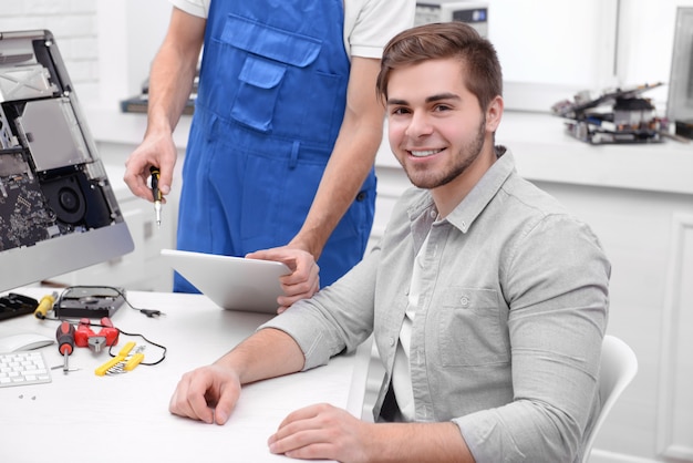 Master showing the repair process to young man in service center